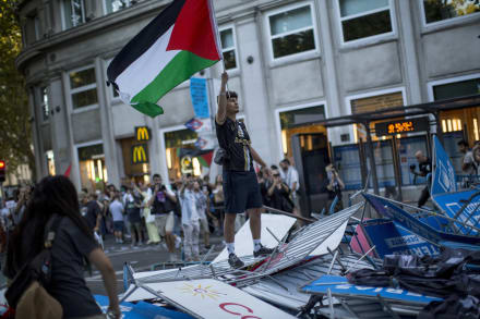 En ung mand er klatret op på en stak barrierer i Madrid for at flage med det palæstinensiske flag i september, hvor den 21. etape af Vuelta a España blev aflyst.