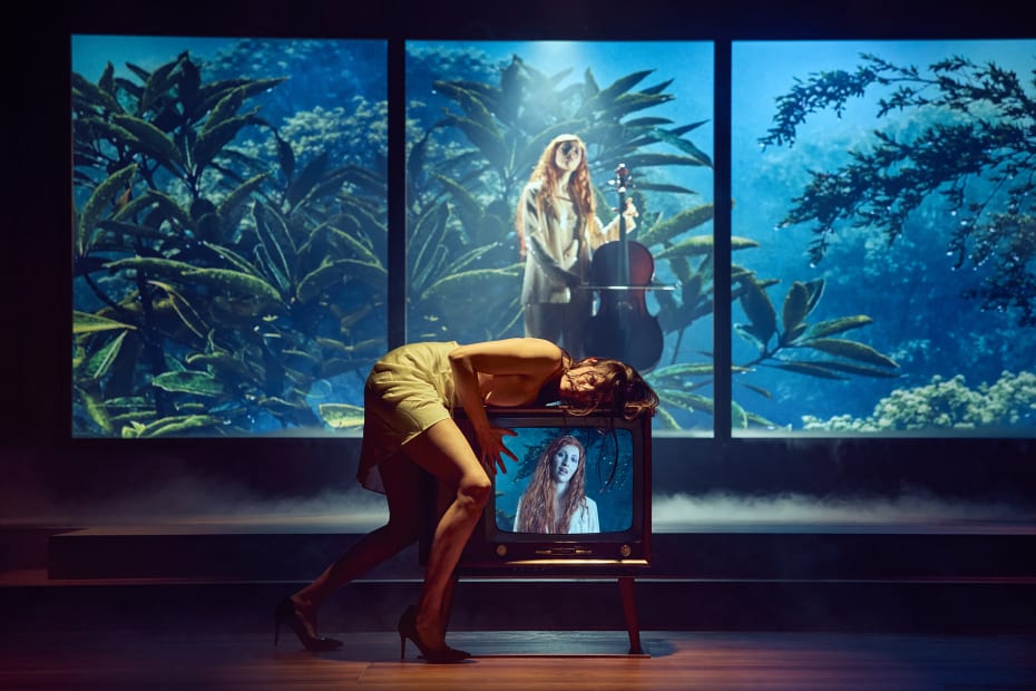 Skuespilleren Nanna Bøttcher udlever sit frustrerede begær op ad hjemmets fjernsyn i sin fantastiske fortolkning af rollen som Fædra, mens musikeren Amanda Drew betragter hende i rollen som Afrodite i Aarhus Teaters stærke opsætning af ’Fædra’.